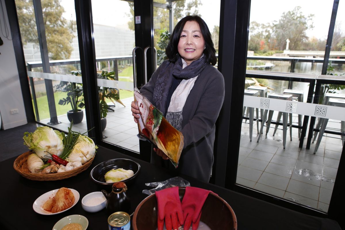 Woman holding bag of spices, standing behind table with food on it