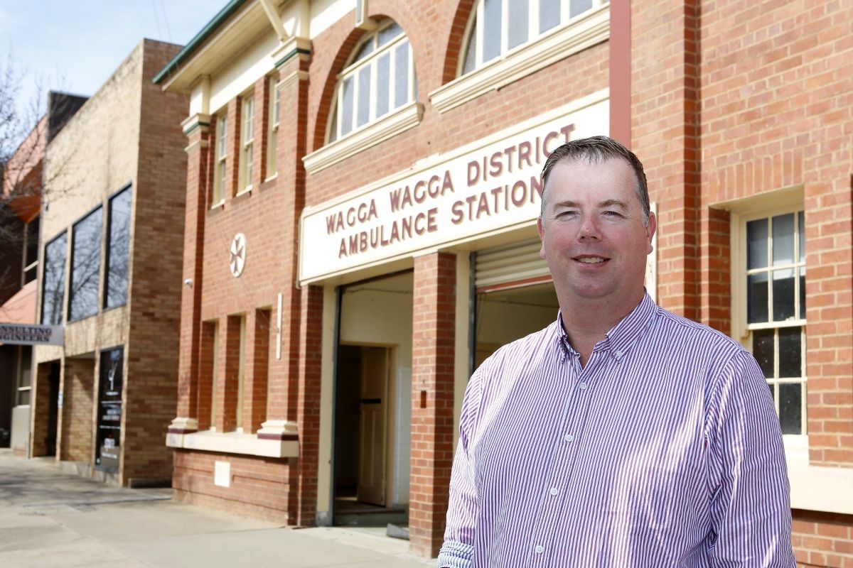 Man standing in front of old ambulance station building