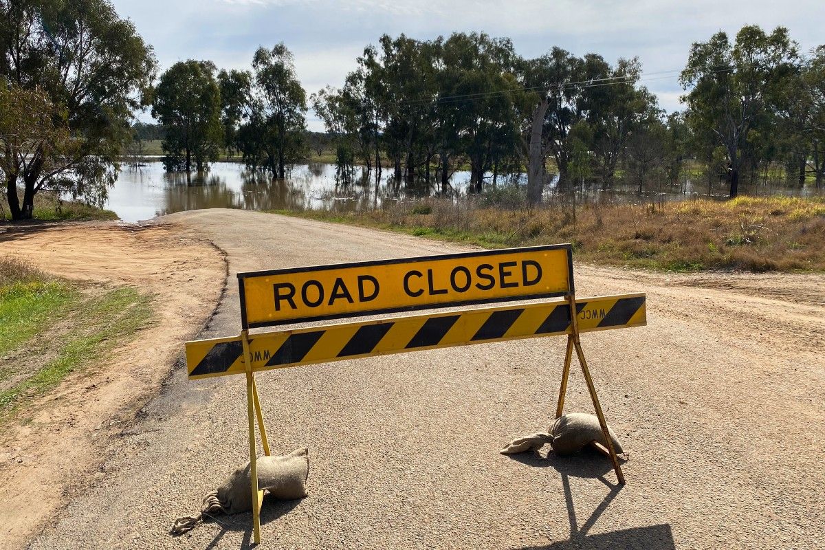 Road closed sign with flood waters in background