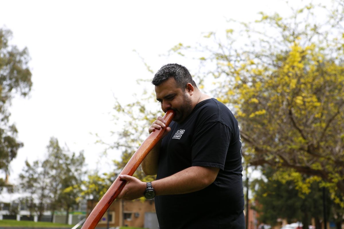 Dane Simpson playing didgeridoo with lagoon in background