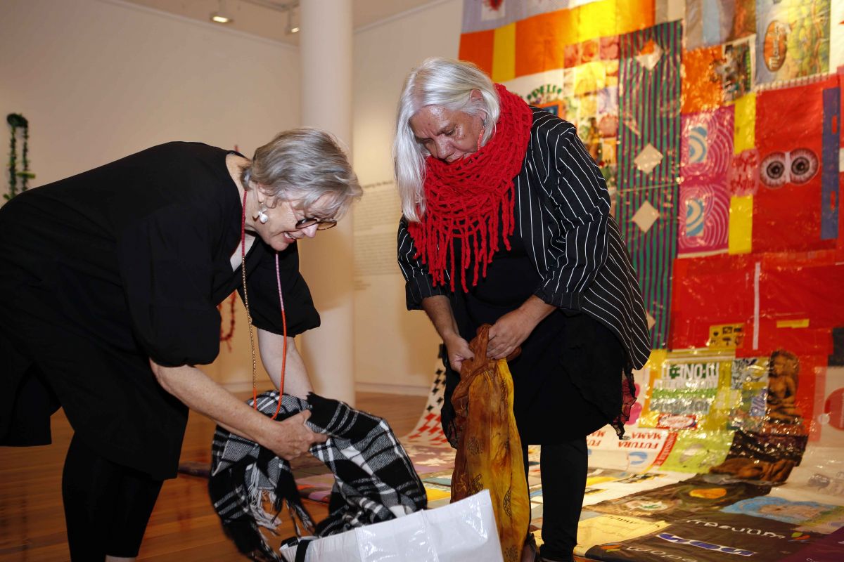Two women looking through bag of colourful clothes at Art Gallery