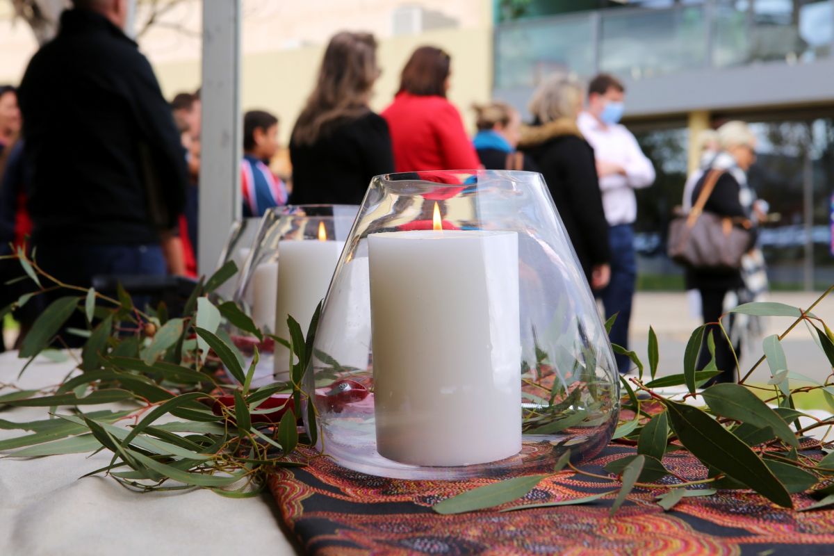 Candles on tables surrounded by Australian flora and people in background