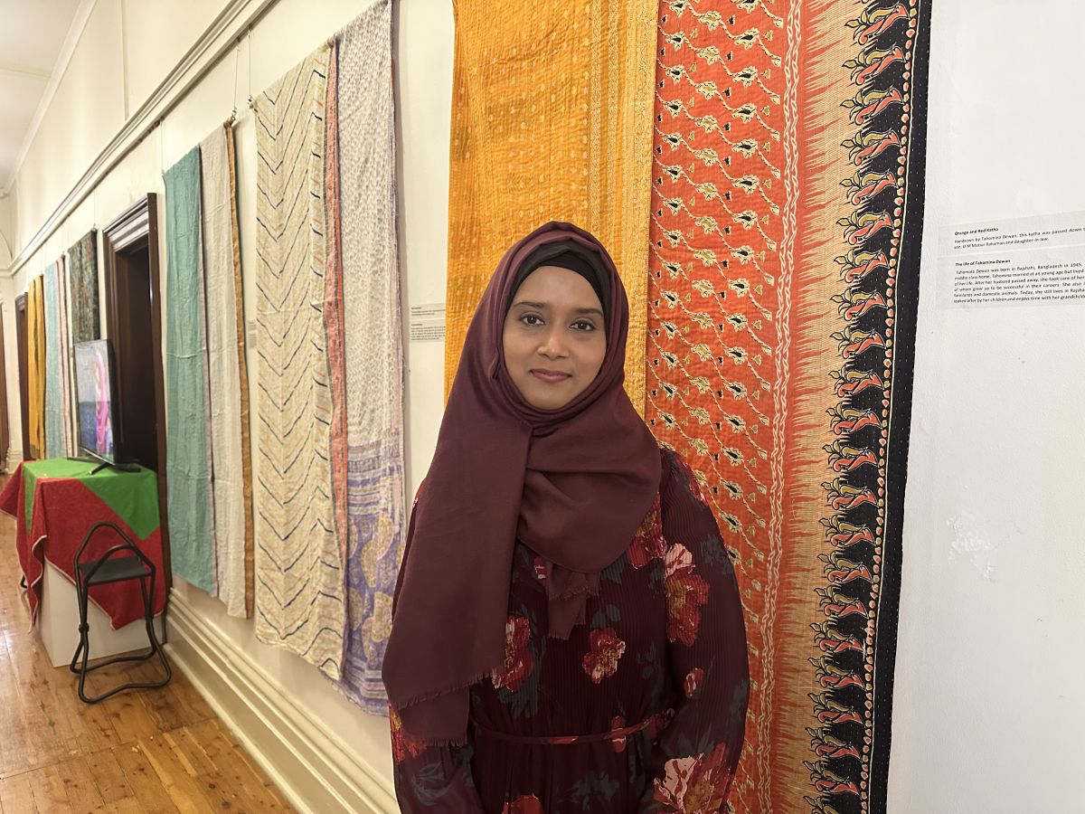 Museum visitor stands in front of Katha display. 