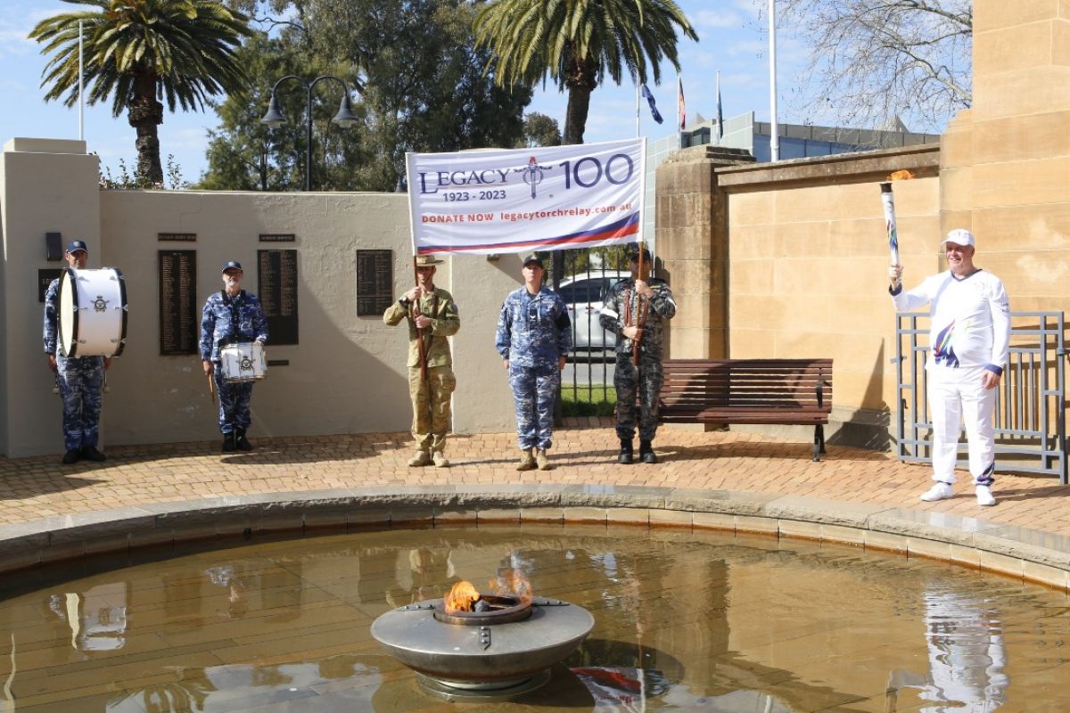 Defence Force personnel carrying Legacy Centenary banner and Wagga Mayor standing inside Hall of Remembrance at Victory Memorial Gardens