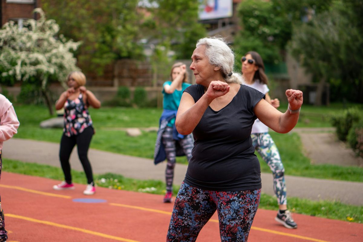 Senior female dancing in outdoor gym class.