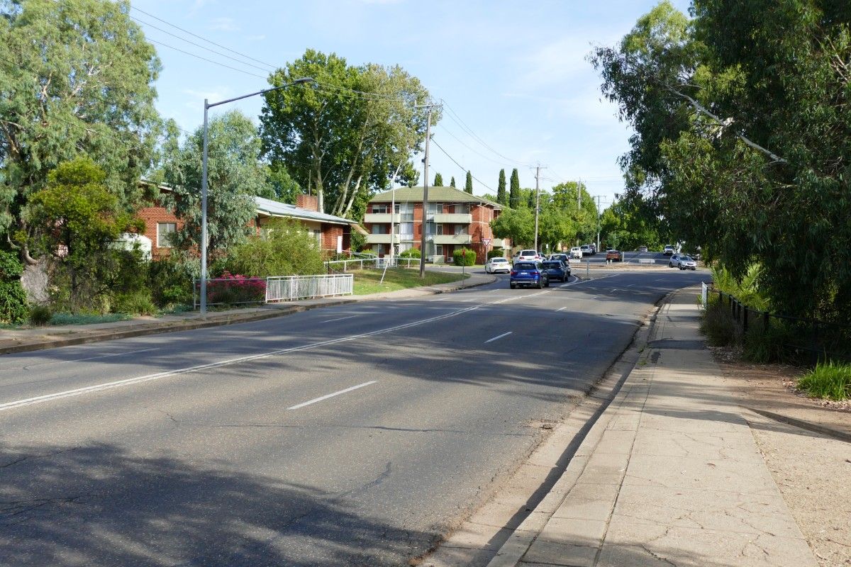 Road in the foreground with vehicles stopped at a roundabout in the background.