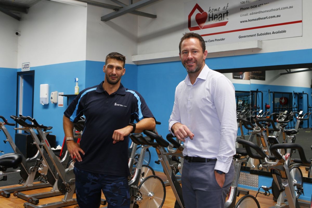 Two staff members stand in a gym.