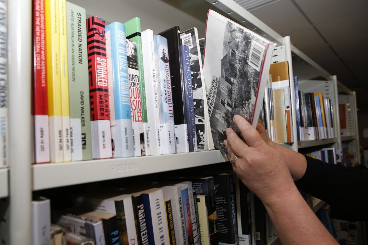 Woman's hand placing a book back on a shelf filled with books