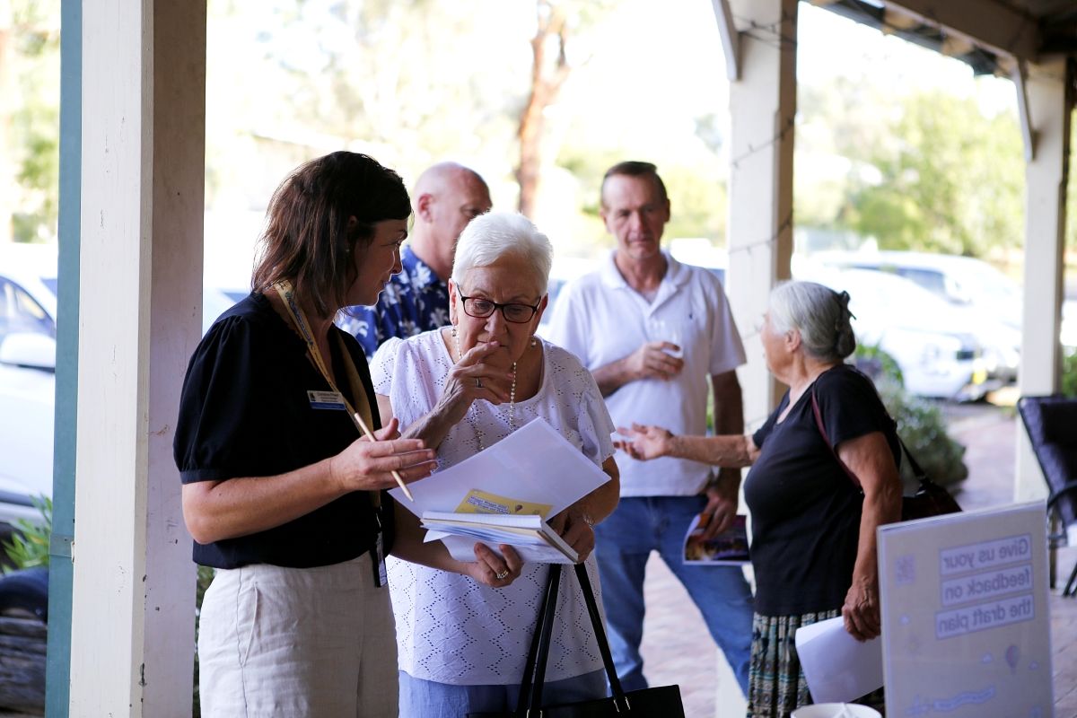 A Council staff member is talking to a resident and they both are looking and gesturing to an open document.