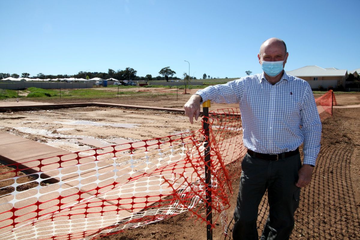 Man standing in front of fenced off area for new playground