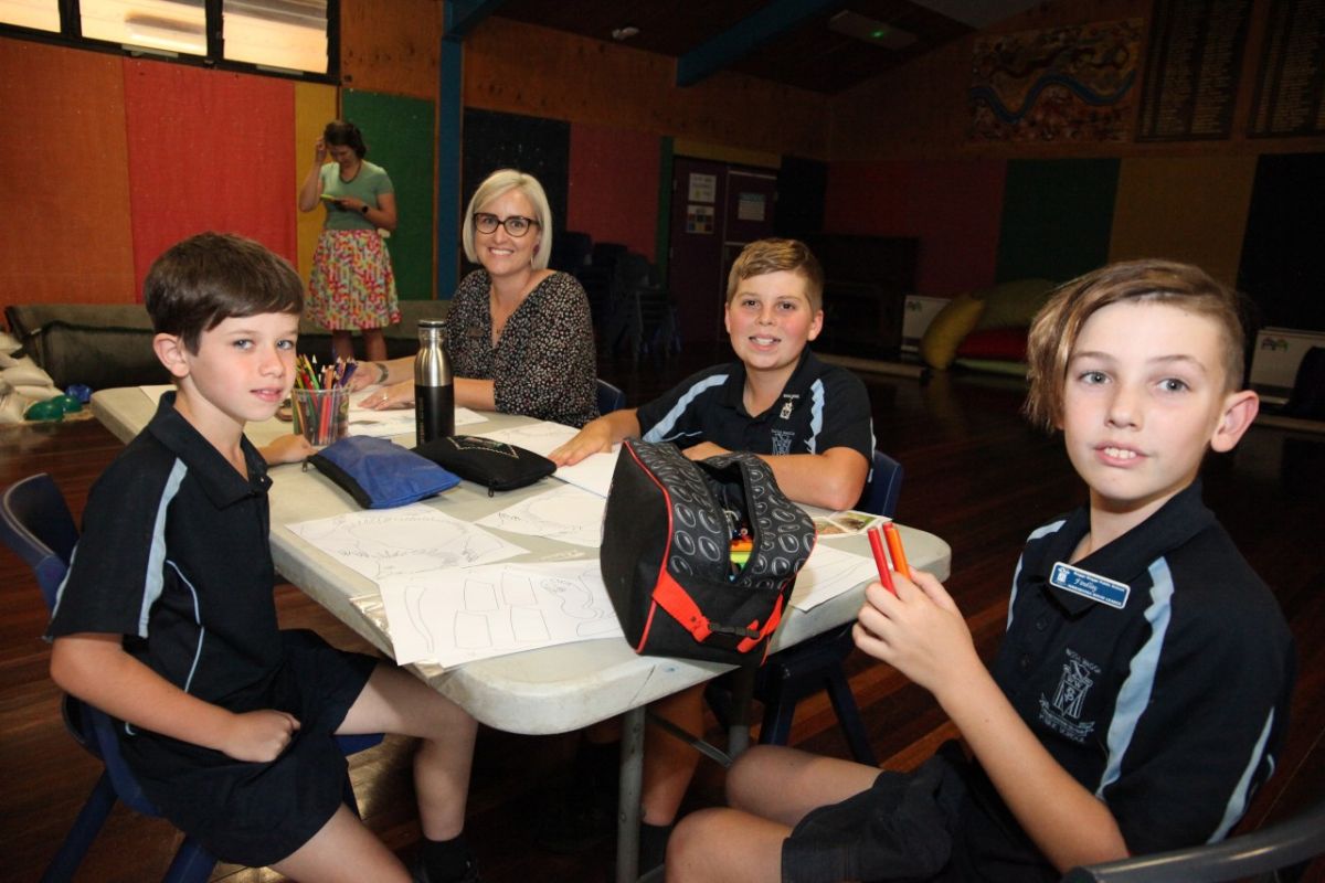 A woman sits at a desk with three young students