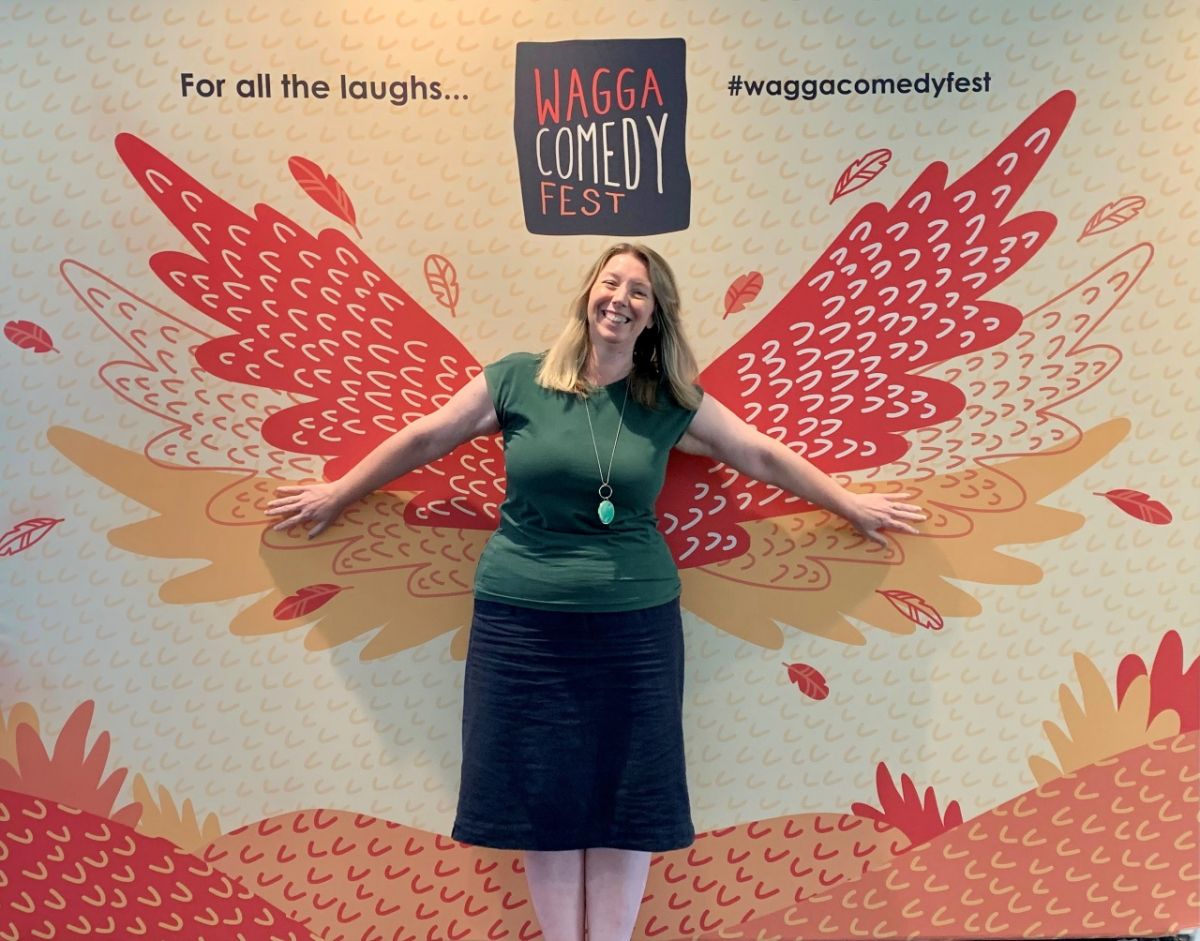 Woman standing in front of promotional sign for Comedy Fest