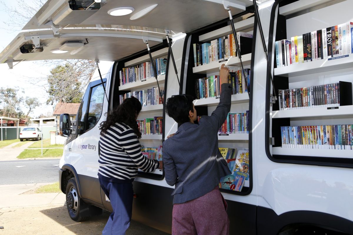 Two female library officers stocking shelves of Agile Library van