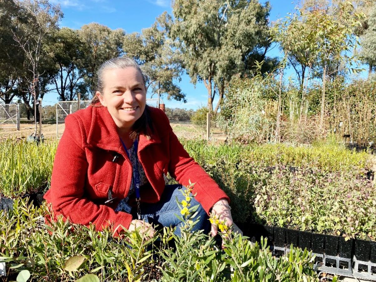 Woman in red jacket surrounded by green seedlings