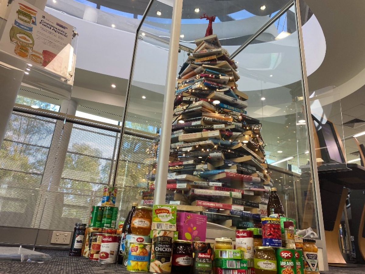 A Christmas tree made of books. Packages of food sit at the base.