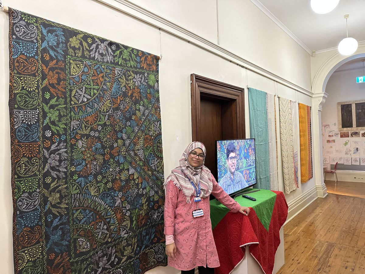 Museum visitor stands in front of Katha display.