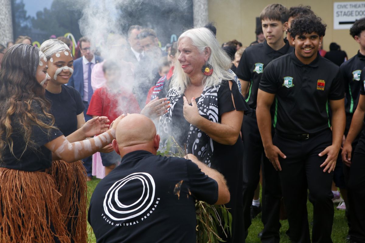 Several local First Nations community members, as well as the wider Wagga Wagga community and Council staff are gathered together waiting to pass through the smoke during the smoke ceremony.