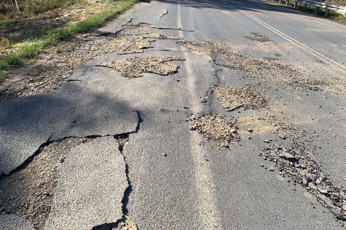 Large cracks and potholes in bitumen road surface