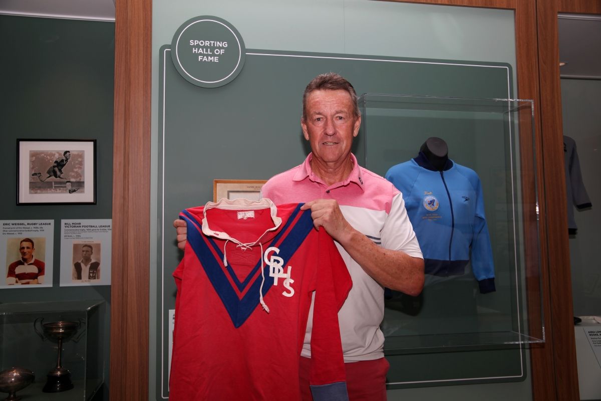 A man stands holding a retro football jersey.