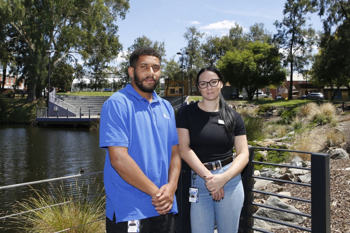 Two people stand outside in front of the Wollundry Lagoon.