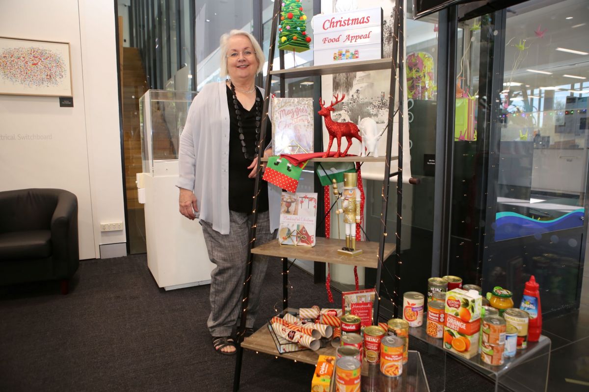 Woman standing beside Christmas decorations and pantry staples
