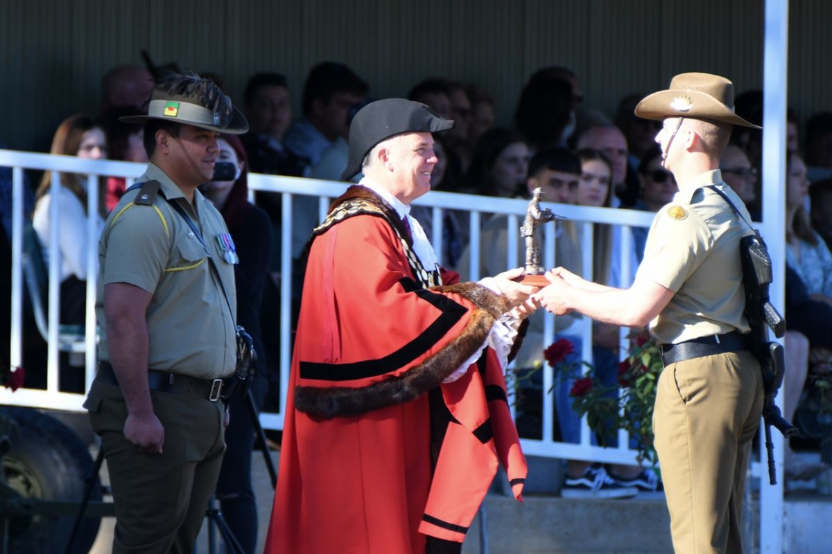 Man in mayoral robes presents award to soldier