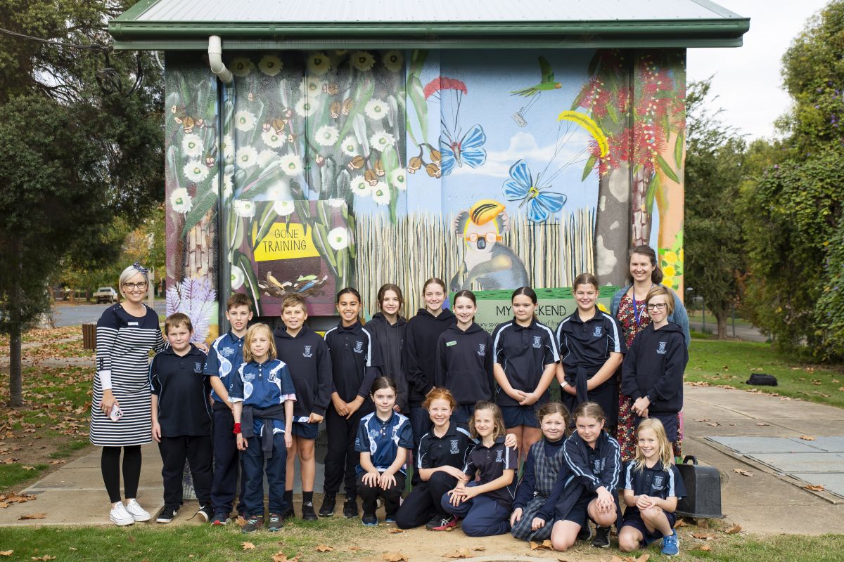 Wagga Public School students and two adults in front of mural on pump station 