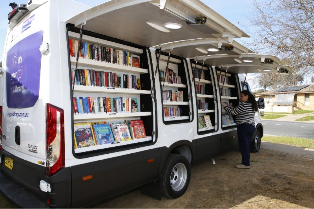 A woman standing beside a van filled with books