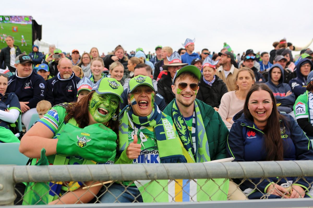 Three female Raiders fans in front row at game, with faces painted green