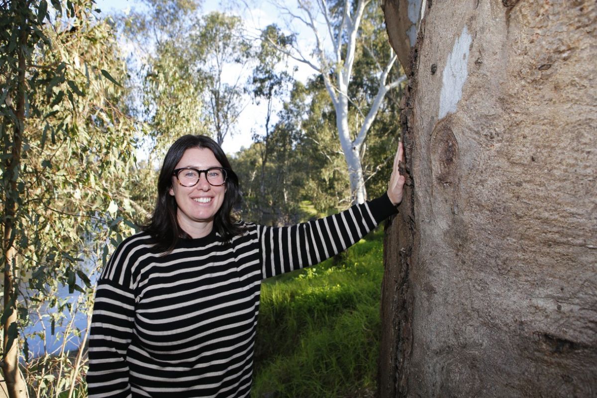 Council Environmental Officer Sam Pascall  standing next to a gum tree with other native trees in background