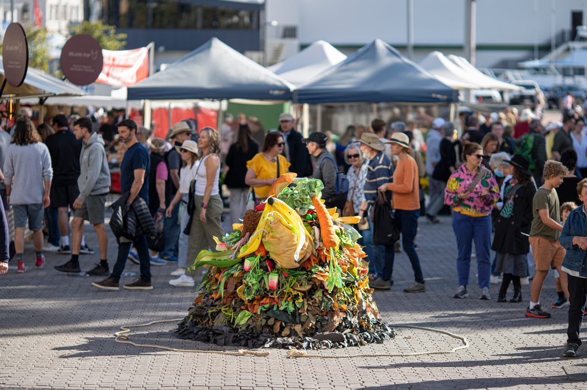 Puppet theatre outfit created to look like compost heap, performing in front of crowd at event.