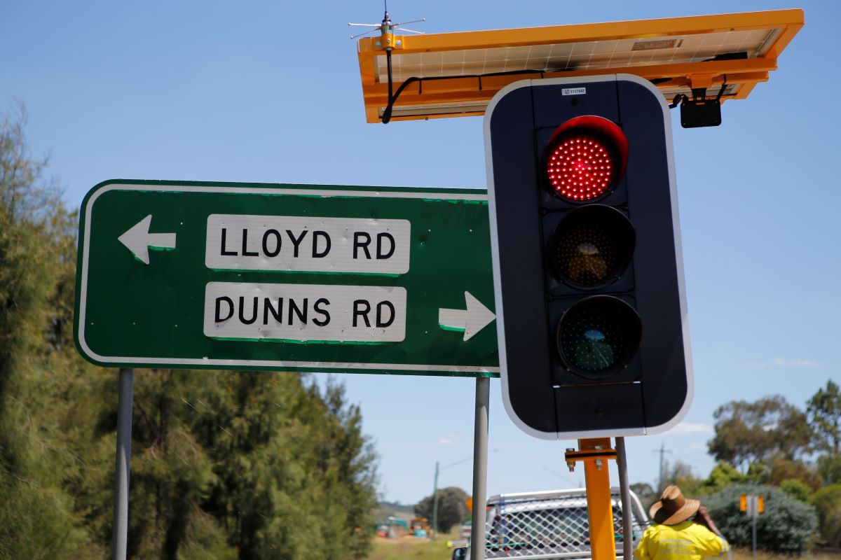 A street sign that says Lloyd Road and Dunns Road. Next to it is a temporary traffic light with the light on red. 