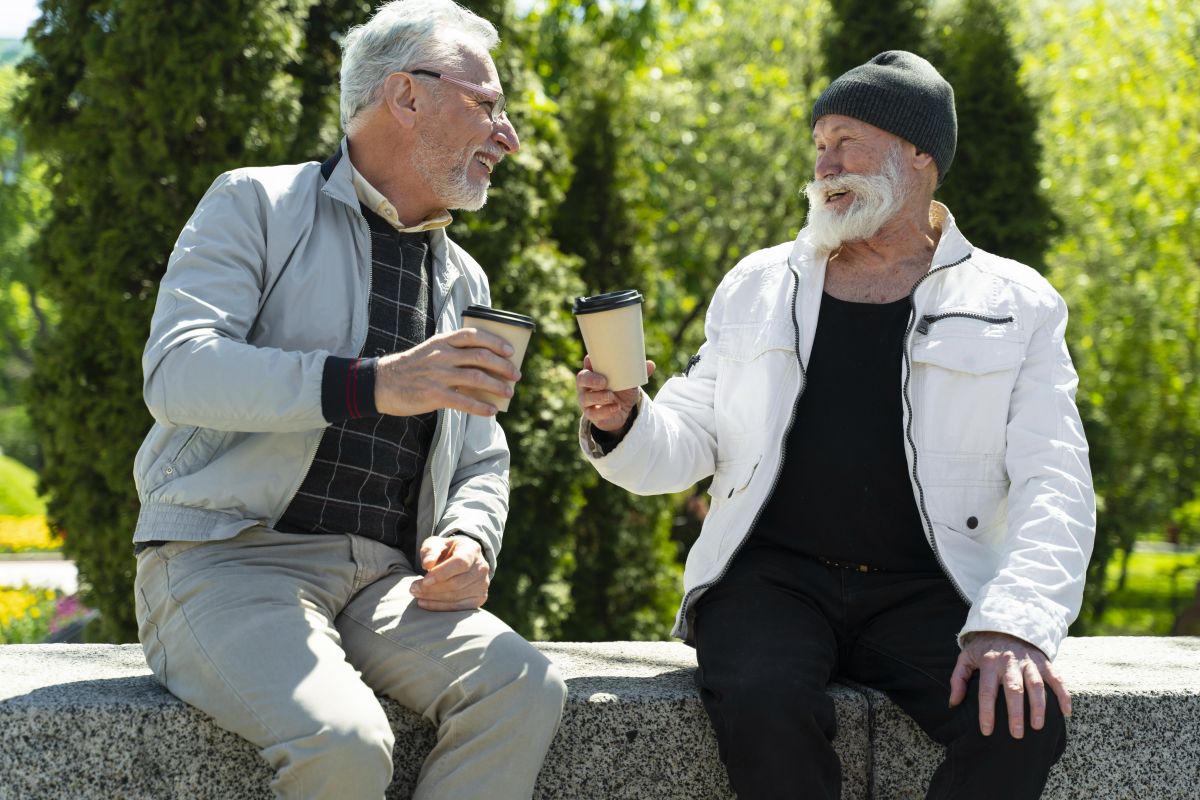 Two elderly men sitting with coffee.
